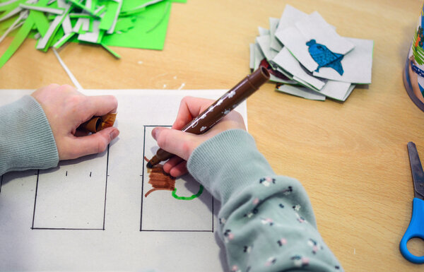 Ein Kind malt mit einem Stift auf einem Blatt Papier.