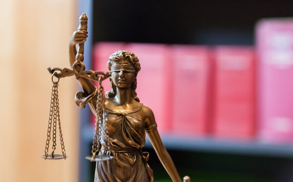 Justitia vor Bücherregal mit Gesetzbüchern