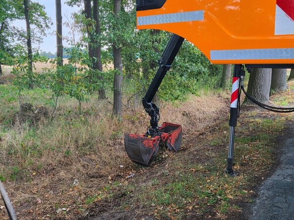 Die Greifschaufel eines Mülltransportfahrzeugs nimmt Müll vom Boden des Parkplatzes auf.